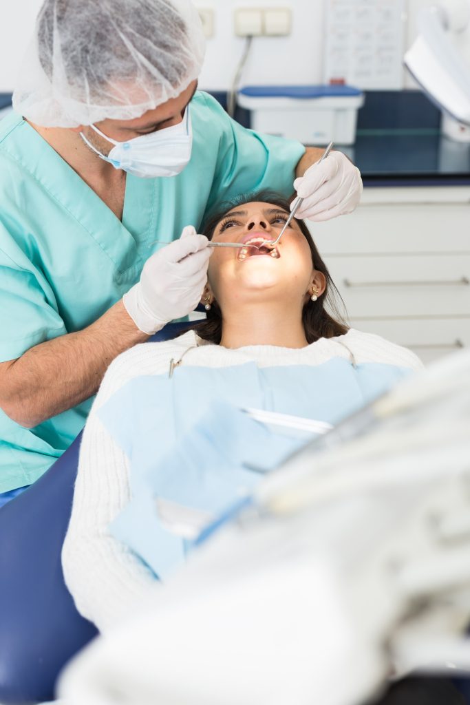 portrait dentist behind patient working with tools