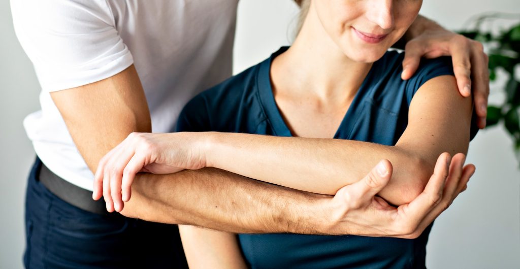 chiropractor aligning woman's shoulder