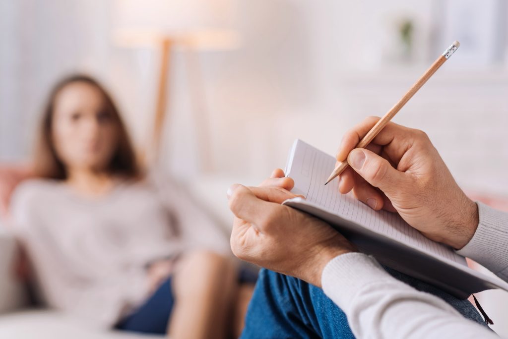 therapist holding notepad taking notes with female patient