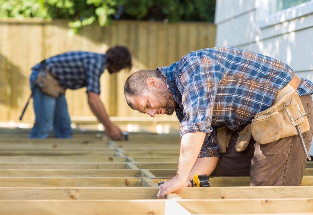 man installing wooden beams outdoors