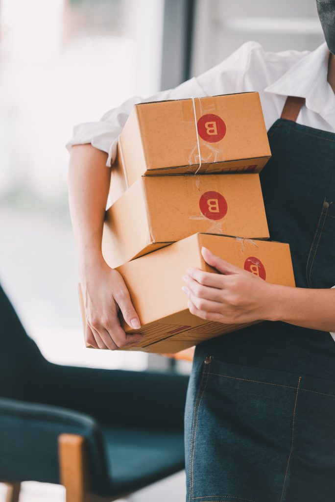 female store owner carrying three boxes