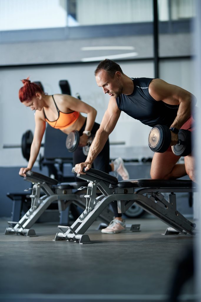 people lifting dumb bells in gym rowing