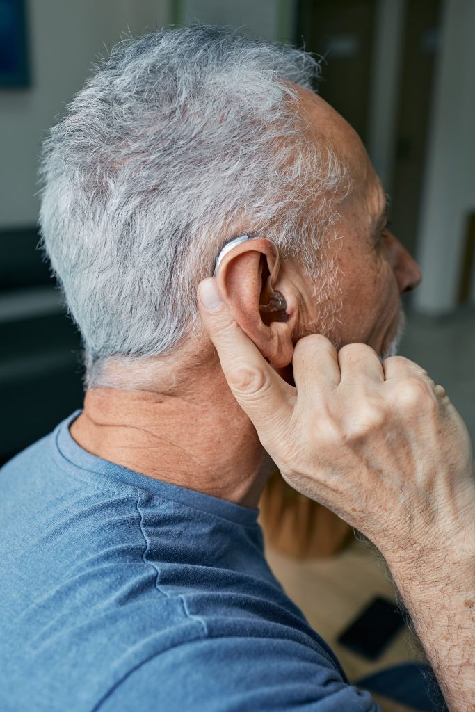 man pointing at hearing aid inserted into ear