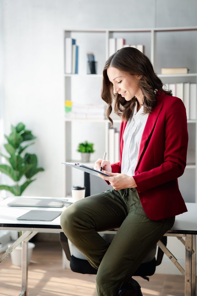 woman sitting on desk reviewing tablet screen