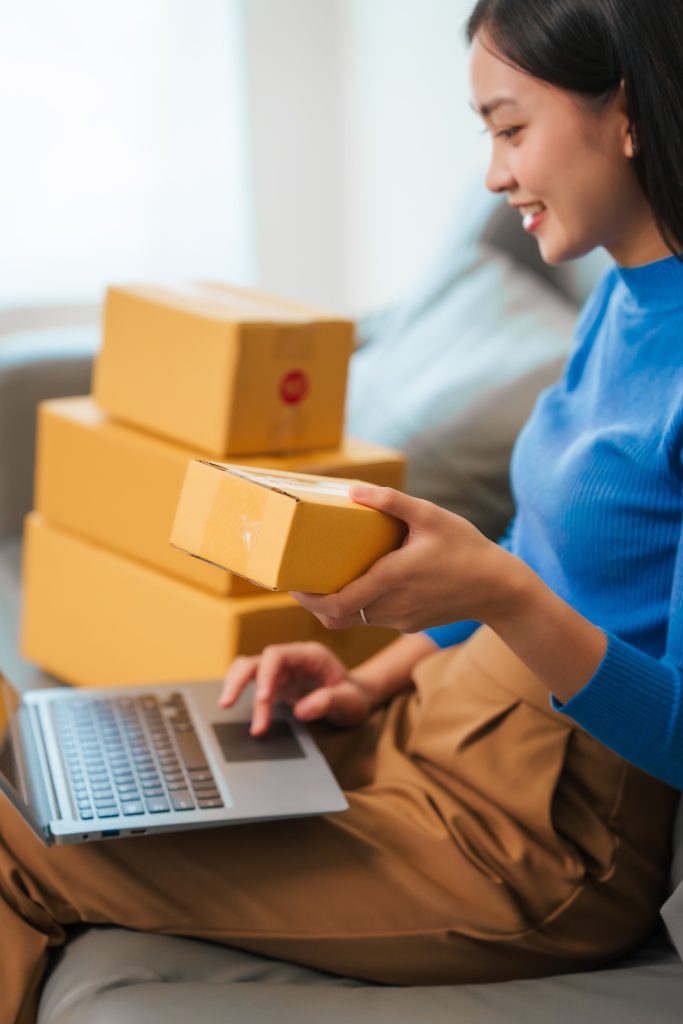 woman holding box filling out info on laptop