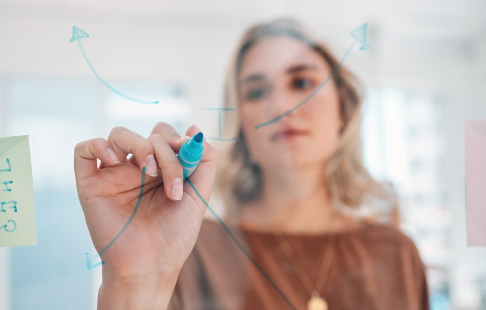 SEO analyst drawing arrow pointing outward on a clear board.